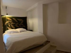 - une chambre avec un lit blanc orné d'une peinture murale dans l'établissement Casa Moncollet, à Roquebrune-Cap-Martin
