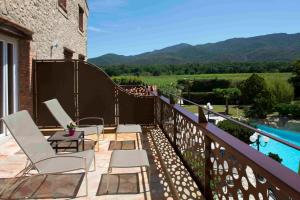 a balcony with chairs and a pool and mountains at Auberge Du Roua in Argelès-sur-Mer