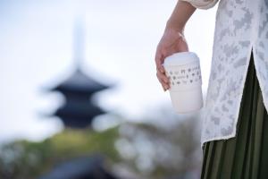 Eine Frau, die eine Tasse Kaffee in der Hand hält. in der Unterkunft OMO3 Kyoto Toji by Hoshino Resorts in Kyoto