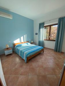een slaapkamer met een bed met blauwe muren en een raam bij Villa il Boschetto in San Vincenzo