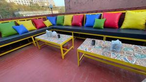 a bench with colorful pillows on a balcony with two tables at Villa Verona in Mumbai