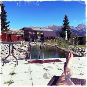 a person with their feet up on the edge of a swimming pool at Hotel Garni Alpendiamant in Fiss