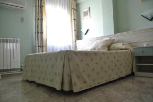 a bedroom with a bed with a blanket on it at Hotel Rausan in Alfajarín