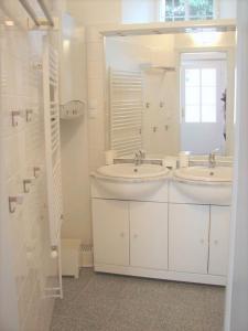 Baño blanco con 2 lavabos y espejo en Bioweingut Hauerhof 99 -apartment 2, en Klosterneuburg