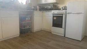 a kitchen with white cabinets and an oven and a counter at Beautiful Bedroom near Barking Railway station in london with good Transport Link direct connect with central london in Barking