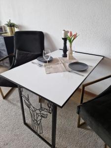 a white table with two chairs and a vase with a flower at Sonnenhang Apartment in Medebach +7 photos