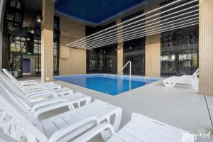 a group of lounge chairs and a pool in a building at Red Sunset z basenem in Pobierowo