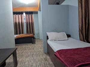 a small room with two beds and a couch at Lama Hotel in Gangtok