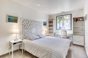 a white bedroom with a bed and a window at Les Palmiers in Palavas-les-Flots