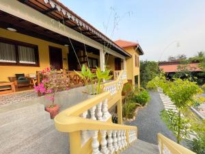 una casa amarilla con una barandilla blanca en un porche en Villa Romduol, en Kampot