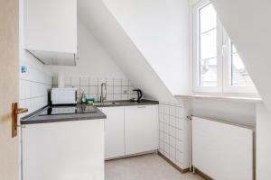 een witte keuken met een wastafel en een raam bij Zentrales charmantes Apartment in Kulmbach