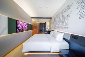 um quarto com uma cama branca e uma parede com desenhos em CitiGO Hotel Beijing ABP em Pequim