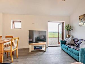 a living room with a blue couch and a table at Huntington - 4 berth renovated barn in Combe Martin