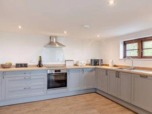 a kitchen with white cabinets and a sink at Huntington - 4 berth renovated barn in Combe Martin
