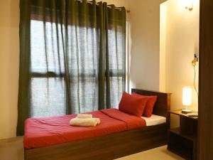 a bedroom with a bed with red sheets and a window at No Fixed Address in Marmagao