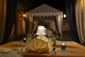una mesa con lámpara, platos y copas de vino en The Garden Ananta Elite, en Rajkot