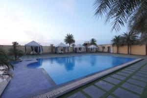 a large swimming pool with palm trees and tents at The Garden Ananta Elite in Rajkot