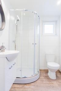 a white bathroom with a shower and a toilet at "AGUŚ" Komfortowe i nowczesne domki w cichej okolicy niedaleko plaży in Ostrowo