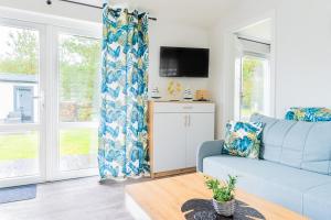 sala de estar con sofá azul y ventanas en "AGUŚ" Komfortowe i nowczesne domki w cichej okolicy niedaleko plaży, en Ostrowo