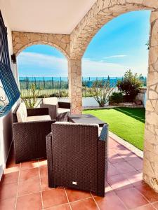 un patio con sillas de mimbre y un arco de piedra en Casa Elena en Sant Pere Pescador