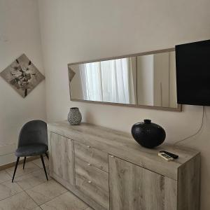 espejo en la parte superior de un tocador de madera con silla en Appartamento con 2 camere, en Taranto