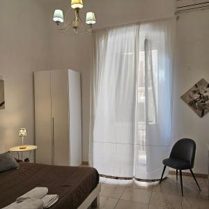 1 dormitorio con 1 cama y ventana con silla en Appartamento con 2 camere, en Taranto