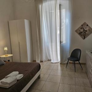 1 dormitorio con 1 cama, 1 silla y 1 ventana en Appartamento con 2 camere, en Taranto