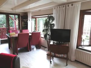 een woonkamer met een televisie en een tafel en stoelen bij Oase rust en privacy op de Veluwe voor 4 personen in Putten