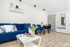 a living room with a blue couch and a table at Apartament BLUE 17 z basenem in Pobierowo