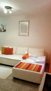 een woonkamer met een witte bank en oranje kussens bij Apartment with a garden Petrovac in Petrovac na Moru