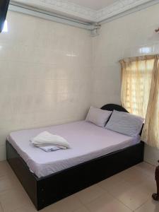 uma cama com lençóis brancos num quarto com uma janela em Ditar Guest House D em Battambang
