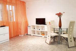 een eetkamer met een tafel en stoelen en een televisie bij Apartment with a garden Petrovac in Petrovac na Moru