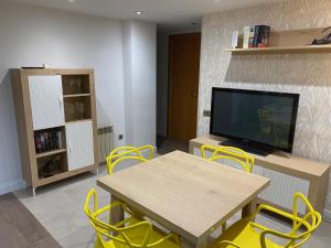 sala de estar con mesa, sillas amarillas y TV en Apartament Sant Jordi, en Sant Joan de Vilatorrada