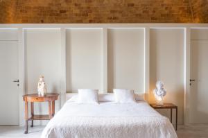 1 dormitorio con cama blanca y pared de ladrillo en Masseria Fontana di Vite, en Matera