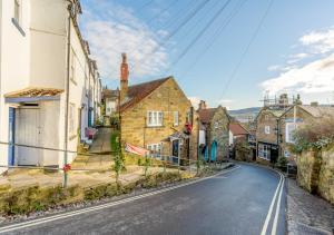 eine leere Straße in einer Kleinstadt mit Häusern in der Unterkunft Alice Cottage in Robin Hood's Bay