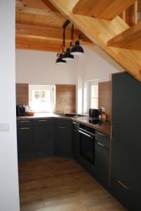 a kitchen with black cabinets and wooden ceilings at Ferienhaus Schirgi in Sankt Kathrein am Offenegg