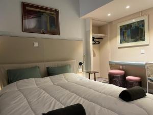a bedroom with a large white bed and two stools at Calming Mountain View Apt with Balcony & Free Parking near Kakopetria in Nicosia