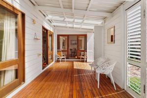 eine Veranda mit 2 Stühlen und einem Tisch auf einem Haus in der Unterkunft Capital Cottage in Narrabundah