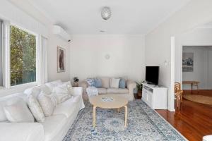 sala de estar con sofá blanco y mesa en Capital Cottage, en Narrabundah