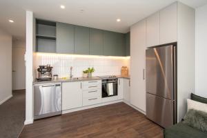 a kitchen with white cabinets and a stainless steel refrigerator at The Mixer Central City Christchurch in Christchurch