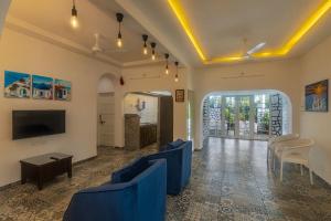 a living room with blue couches and a tv at Stayscape Casa Santorini 4BHK Lonavala in Oxel