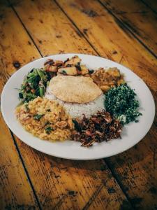 un plato de comida con arroz y verduras en una mesa de madera en Hive Ella - Hostel, en Ella