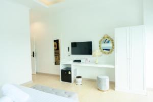 a white bedroom with a bed and a tv at Marble Arch De Loei Hotel in Loei