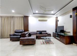a living room with a leather couch and a tv at Fortune pent House Villa in Hyderabad