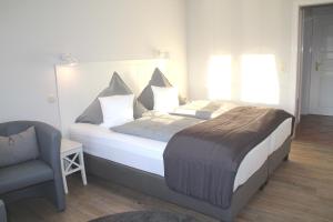 a bedroom with a large bed and a chair at Landhaus Nordstern Hotel garni in Utersum +31 photos