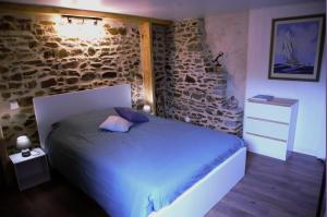 sypialnia z łóżkiem i kamienną ścianą w obiekcie Maisonnette et gîte proches de la mer w mieście Plouha