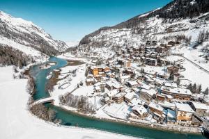 un village recouvert de neige à côté d'une rivière dans l'établissement CASA-Chalet du Parc Cosy apartment in Tignes with garden, à Tignes