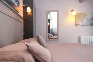 a bedroom with a bed with pillows and a mirror at La Martinoise Patio in Saint-Martin-de-Ré