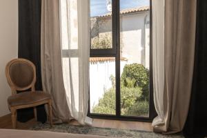 a bedroom with a window with a chair and a chair at La Martinoise Patio in Saint-Martin-de-Ré