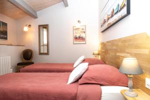 two beds in a hotel room with red sheets at La Martinoise Patio in Saint-Martin-de-Ré